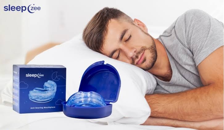 SleepZee mouthpiece and blue case beside a man resting on a white pillow